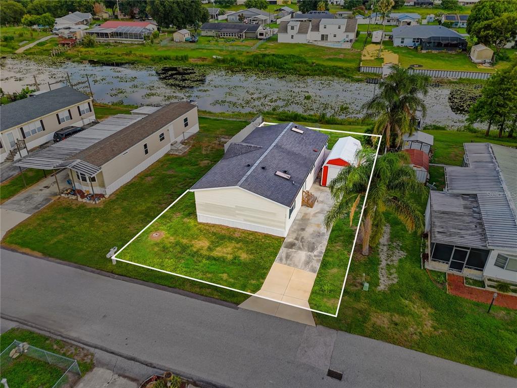 An aerial view shows a single-story house with a driveway, shed, and backyard pond — 338 1ST AVENUE N, LAKE WALES, FL