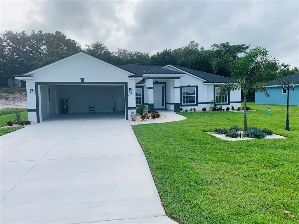 A single-story house with a white exterior, dark trim, and an attached two-car garage — 120 CLINTON AVENUE, LAKE PLACID, FL