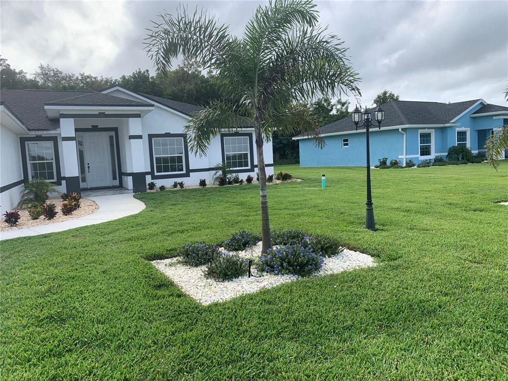 A white house with dark trim and a palm tree in the front yard — 120 CLINTON AVENUE, LAKE PLACID, FL