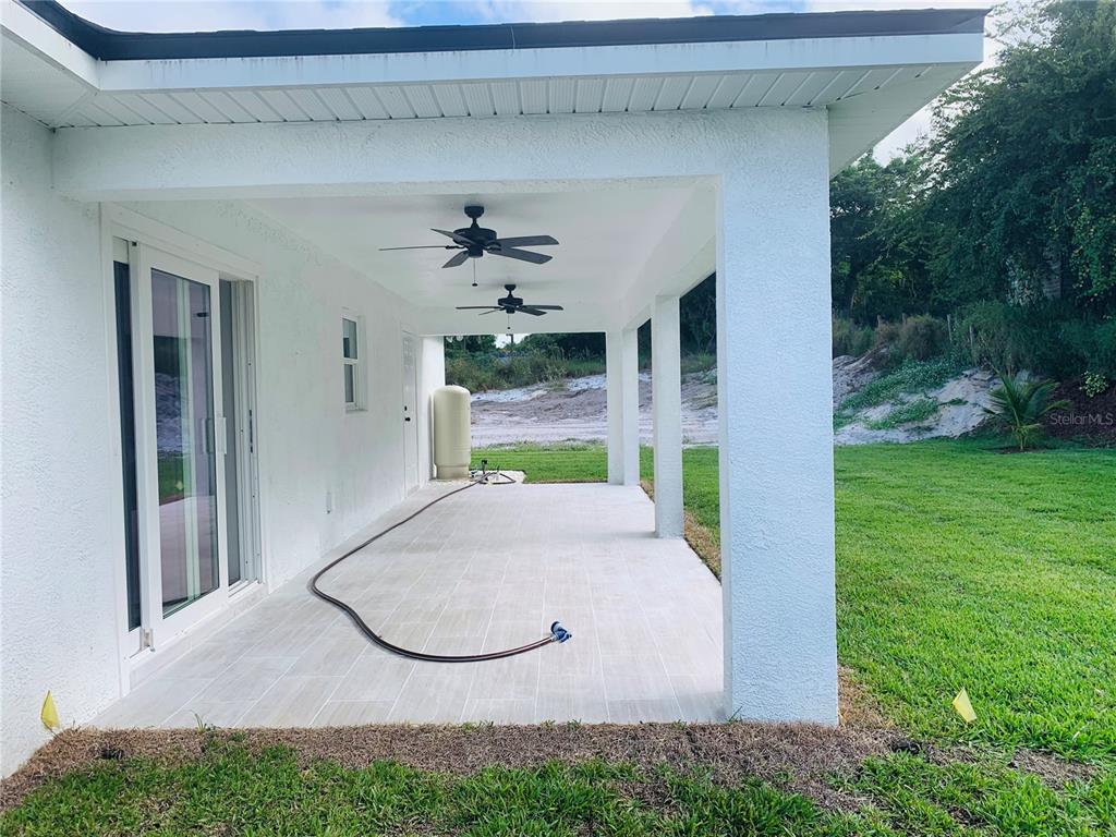 A covered patio with tiled flooring, two ceiling fans, and a water tank — 120 CLINTON AVENUE, LAKE PLACID, FL