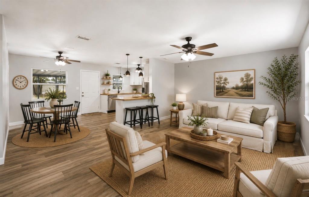 An open-concept living and dining area features light wood flooring, neutral furniture, and a kitchen — 12106 SE 74TH TERRACE, BELLEVIEW, FL