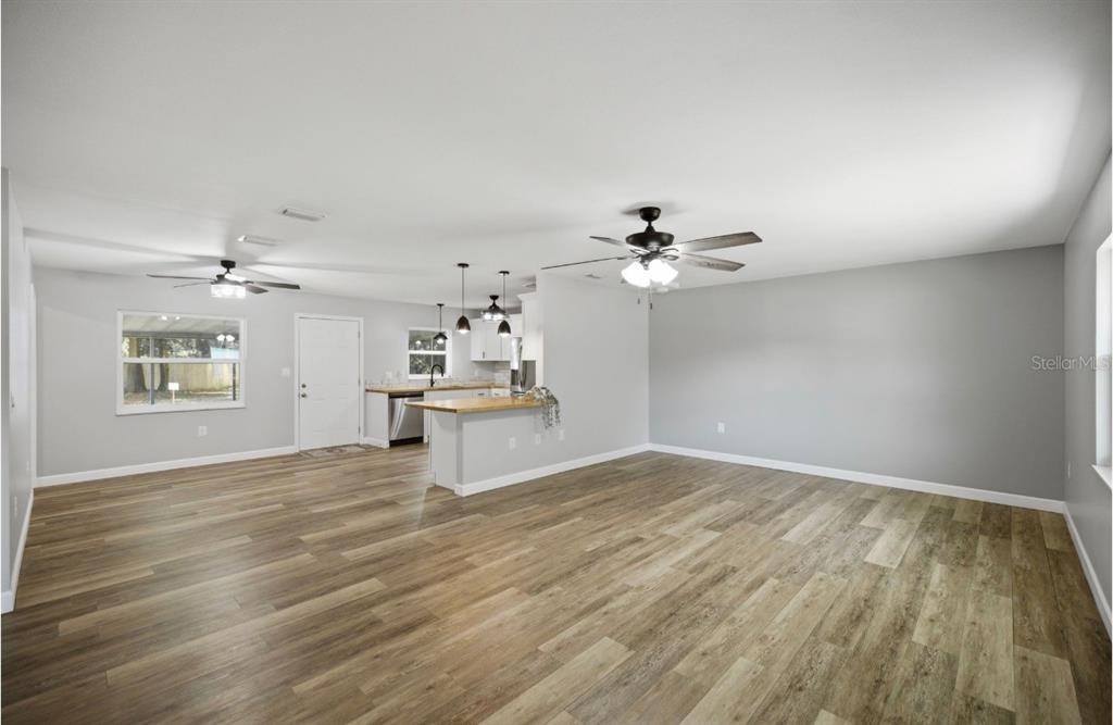 An open-concept living area features light gray walls, wood-look flooring, and a kitchen with pendant lighting — 12106 SE 74TH TERRACE, BELLEVIEW, FL