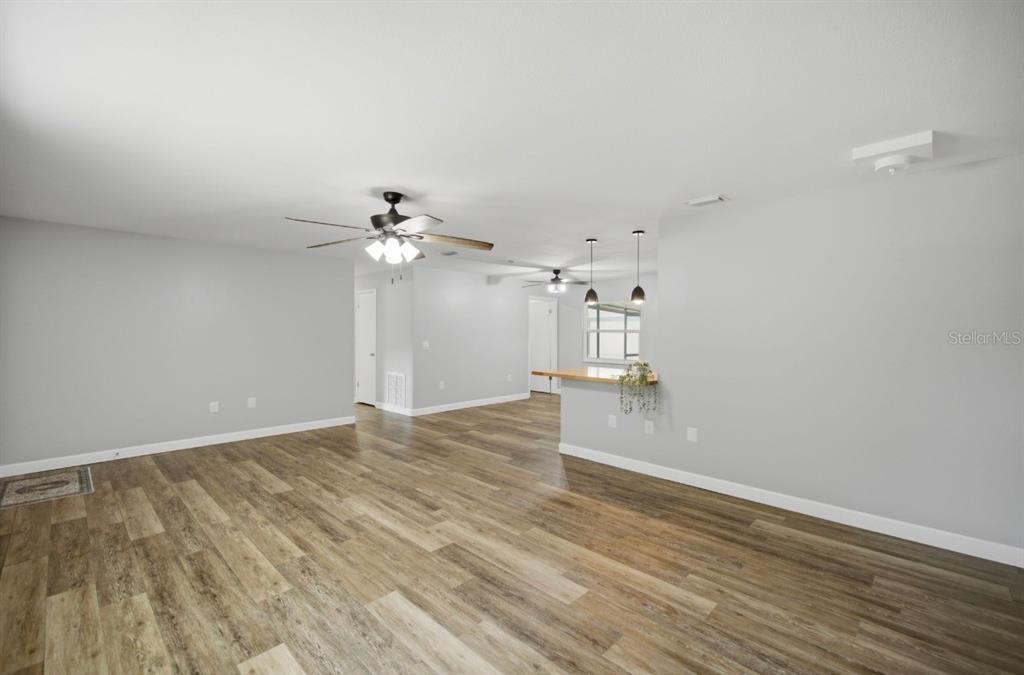 An open-concept living area features light gray walls, wood-look flooring, and two ceiling fans — 12106 SE 74TH TERRACE, BELLEVIEW, FL