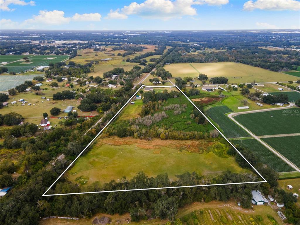 An aerial view shows a large, triangular plot of land with trees and open fields — 1103 COLSON ROAD, PLANT CITY, FL