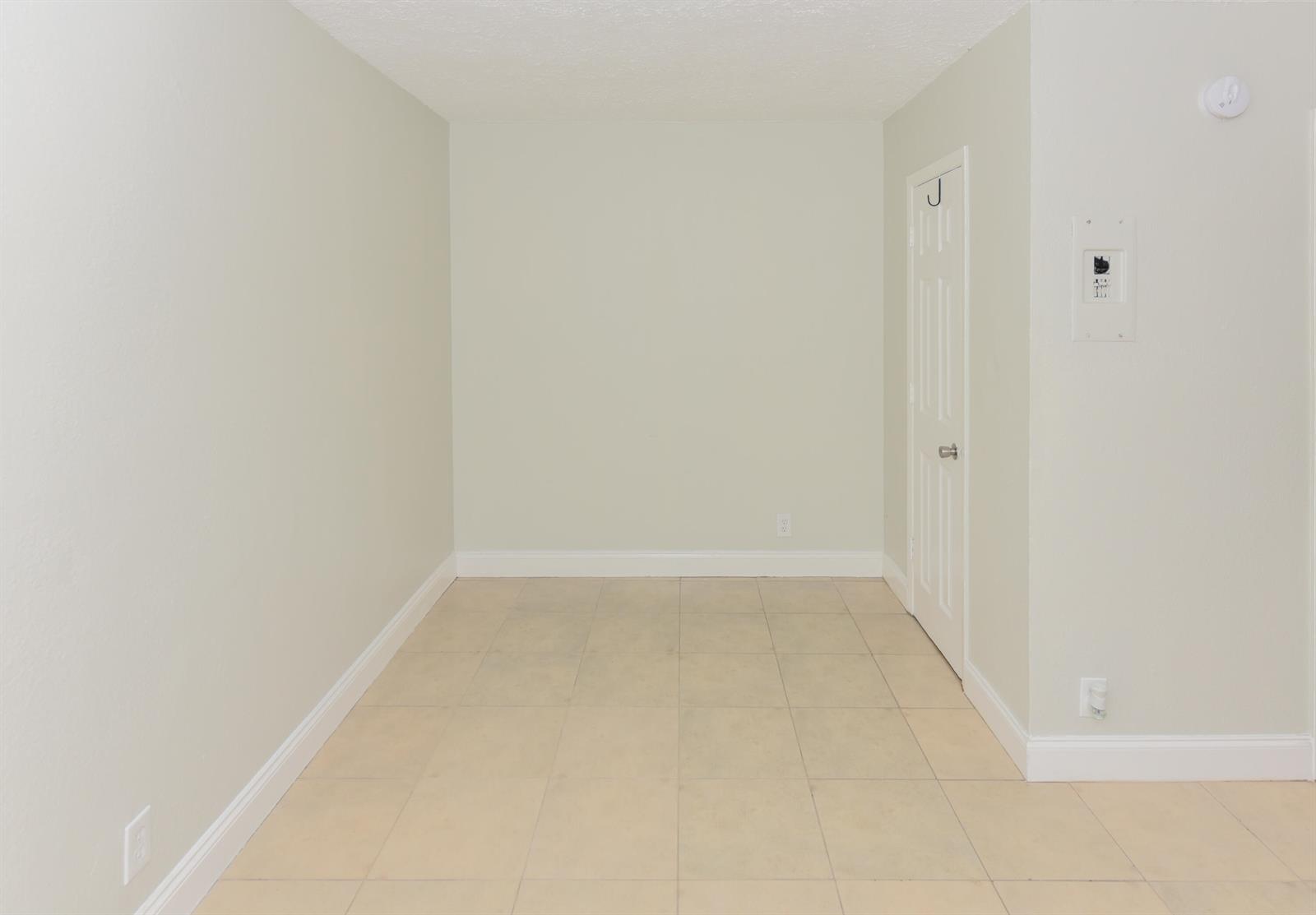 An empty room with light-colored walls, tile flooring, a window air conditioner, and two doorways — 605 N Federal Highway # 8, FL 33460, FL