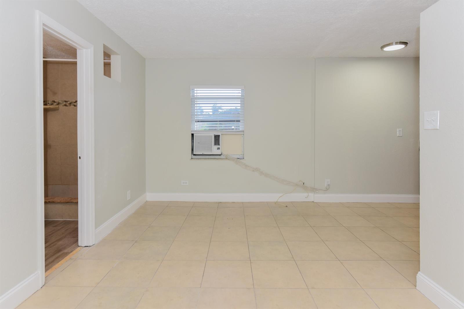 An empty room features light-colored walls, beige tile flooring, and a white interior door — 605 N Federal Highway # 8, FL 33460, FL