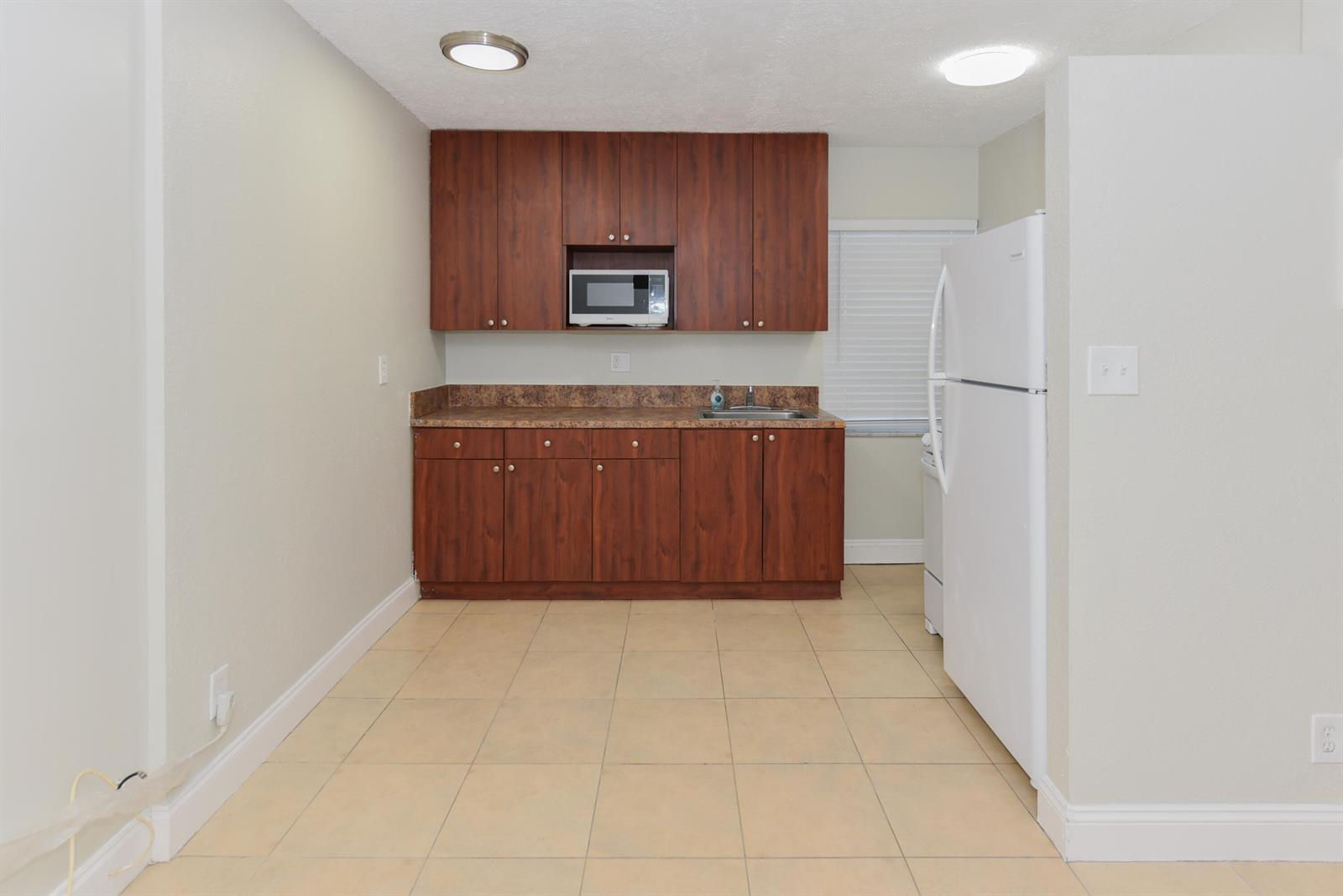 An empty room with light-colored tile flooring, a window air conditioning unit, and a doorway — 605 N Federal Highway # 8, FL 33460, FL
