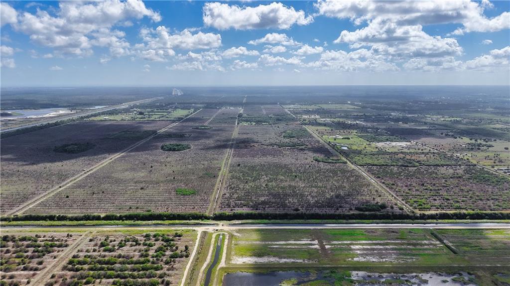 An aerial view shows a large, flat expanse of agricultural land divided by straight roads — FELLSMERE, FL