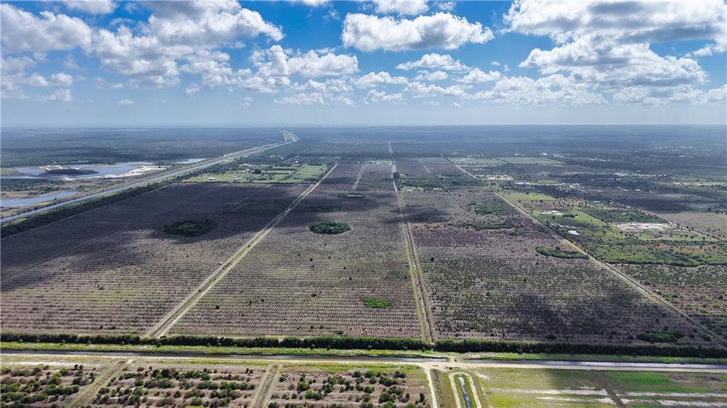 An aerial view shows a large, flat agricultural field divided by irrigation canals and roads — FELLSMERE, FL