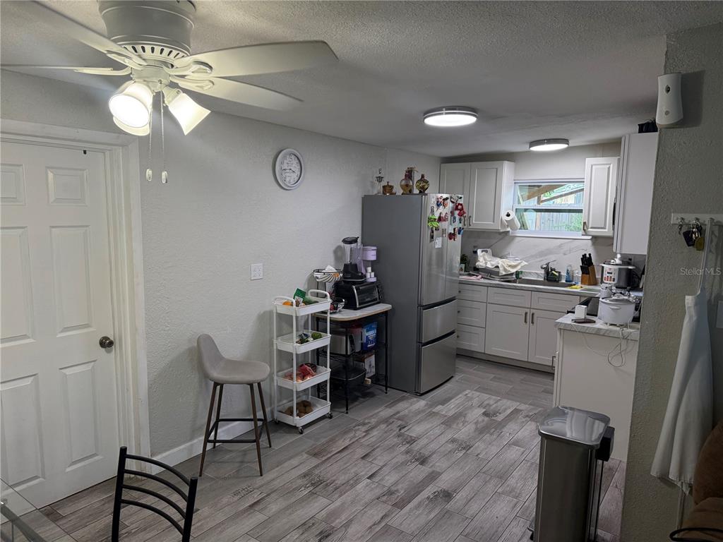 A kitchen features white cabinets, stainless steel appliances, and gray wood-look flooring — 11113 102ND LANE, LARGO, FL