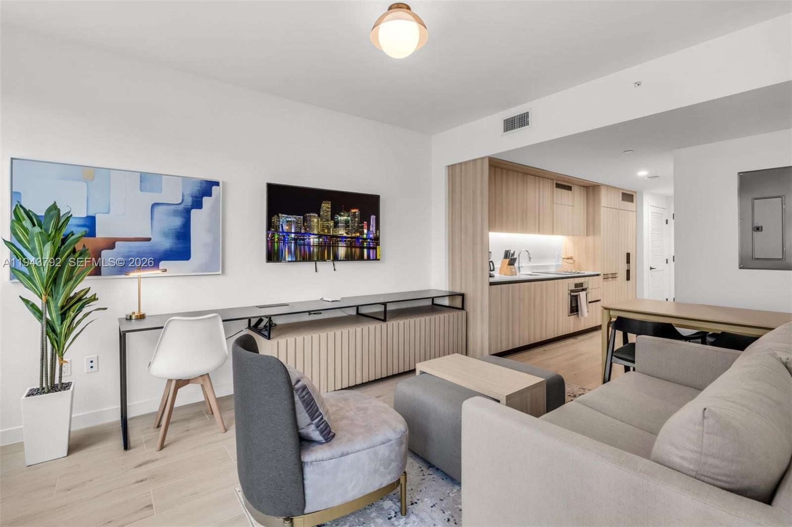 A modern living room with a kitchen, television, desk, and neutral furniture — 225 N Miami Ave # 301, Miami FL 33128, MIAMI, FL