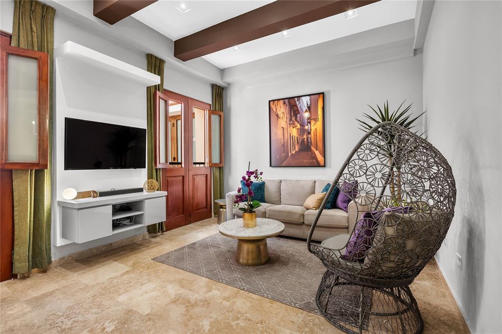 A living room features a beige sofa, a hanging chair, a television, and wood-beamed ceilings — 311 LUNA ST UNIT 202, SAN JUAN, PR