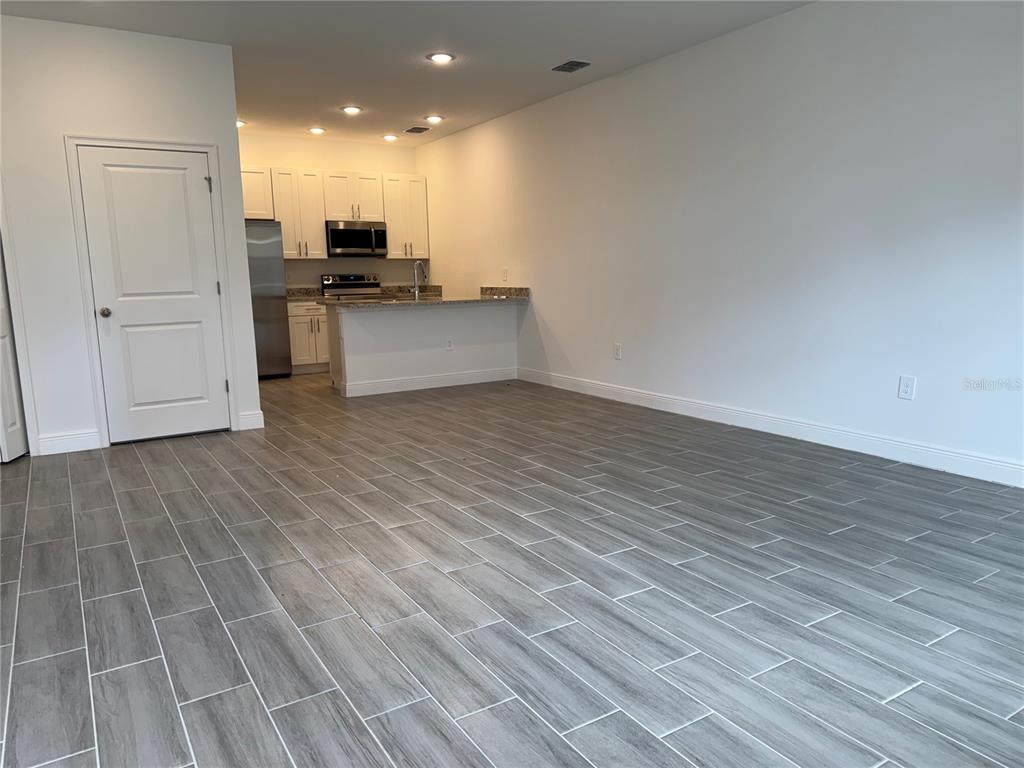 A kitchen with white cabinets and a breakfast bar overlooks an open living area — 1602 CUMIN DRIVE UNIT 1602, POINCIANA, FL
