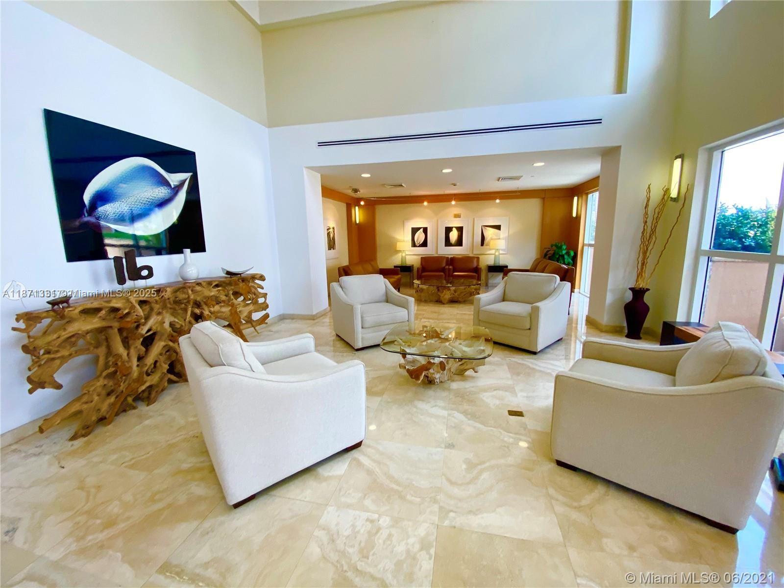 A spacious lobby features cream-colored armchairs, a glass-topped root wood coffee table, and marble flooring — 2080 S Ocean Dr # 604, Hallandale Beach FL 33009, HALLANDALE BEACH, FL
