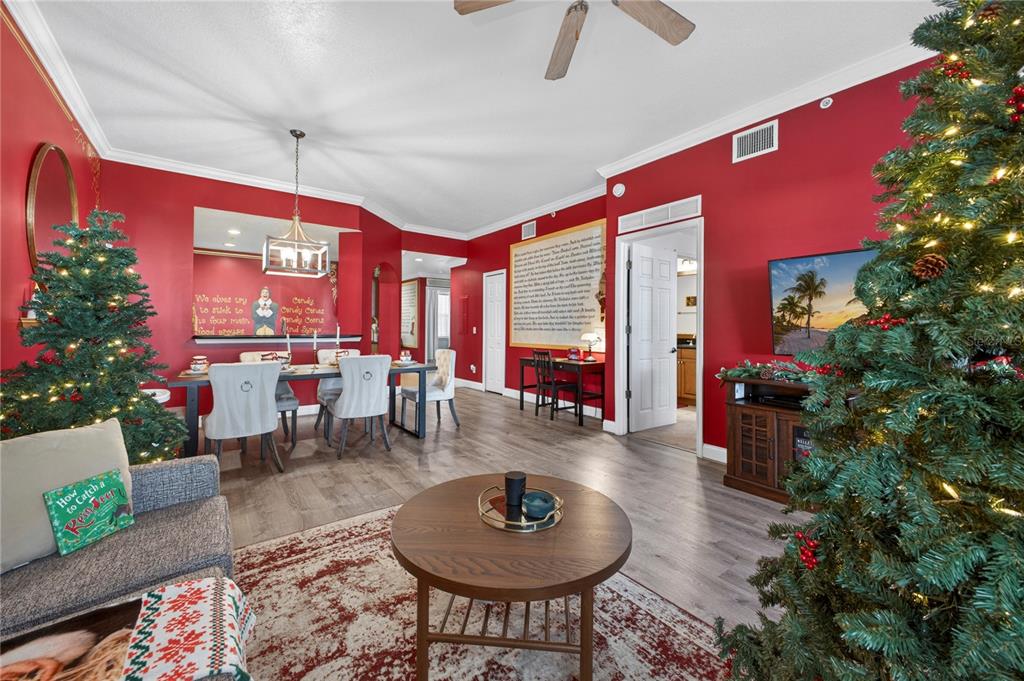 A living and dining area with red walls, wood-look flooring, and two decorated Christmas trees — 7521 MOURNING DOVE CIRCLE UNIT 103, REUNION, FL