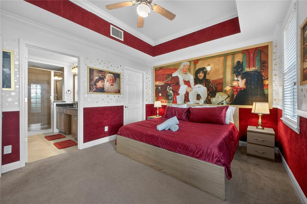 A bedroom features a Santa-themed mural, red walls, a ceiling fan, and an attached bathroom — 7521 MOURNING DOVE CIRCLE UNIT 103, REUNION, FL