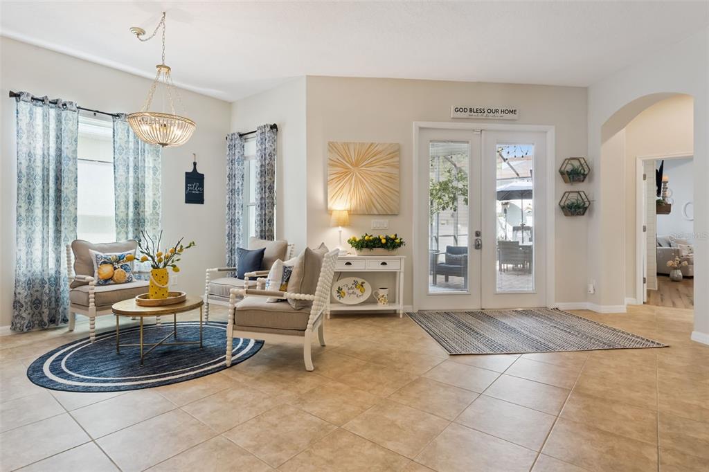A bright living room features tile floors, two armchairs, a coffee table, and glass doors — 420 PARK LAKE DRIVE, WINTER SPRINGS, FL