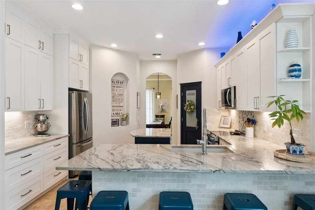 A kitchen with white cabinets, marble countertops, a blue pantry door, and blue bar stools — 420 PARK LAKE DRIVE, WINTER SPRINGS, FL