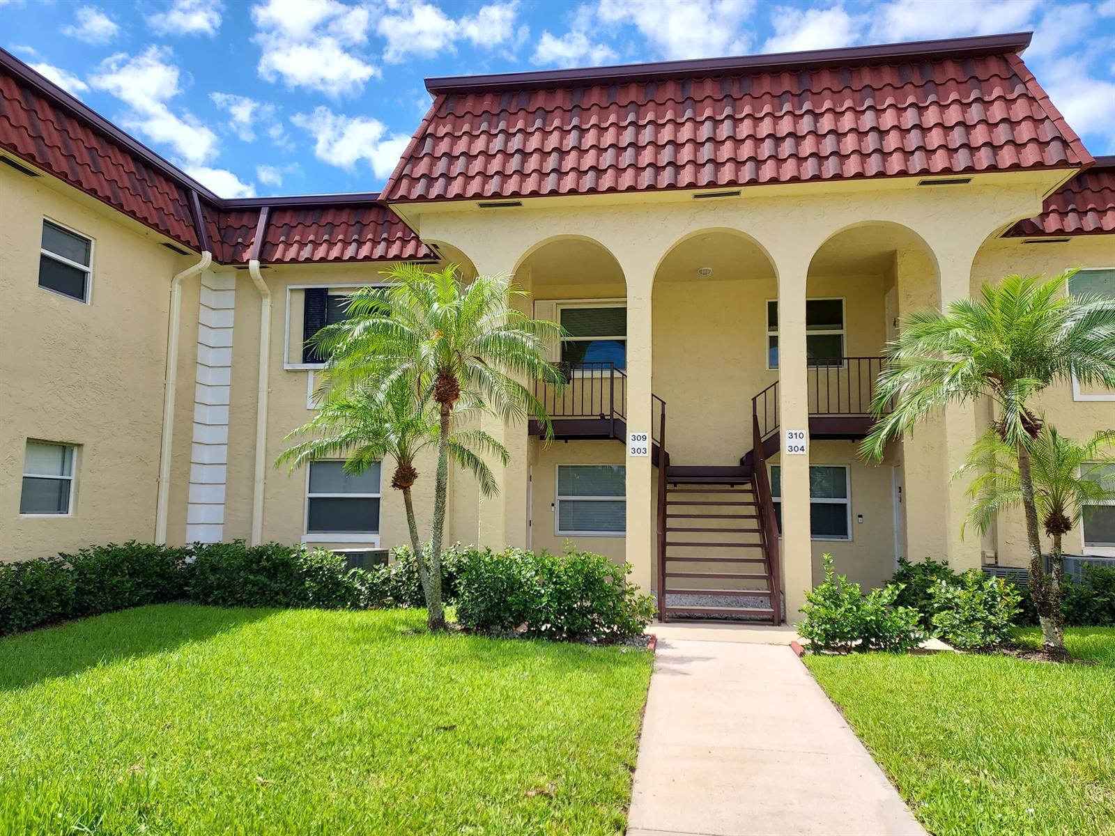 A two-story apartment building features a red tile roof, arched entryways, and exterior staircases — 717 S Us Hwy 1 Unit 309, Jupiter FL 33477, JUPITER, FL