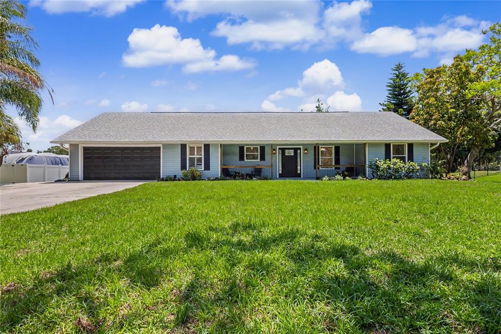A single-story light blue house with a gray shingled roof and an attached garage — 601 136TH COURT E, BRADENTON, FL