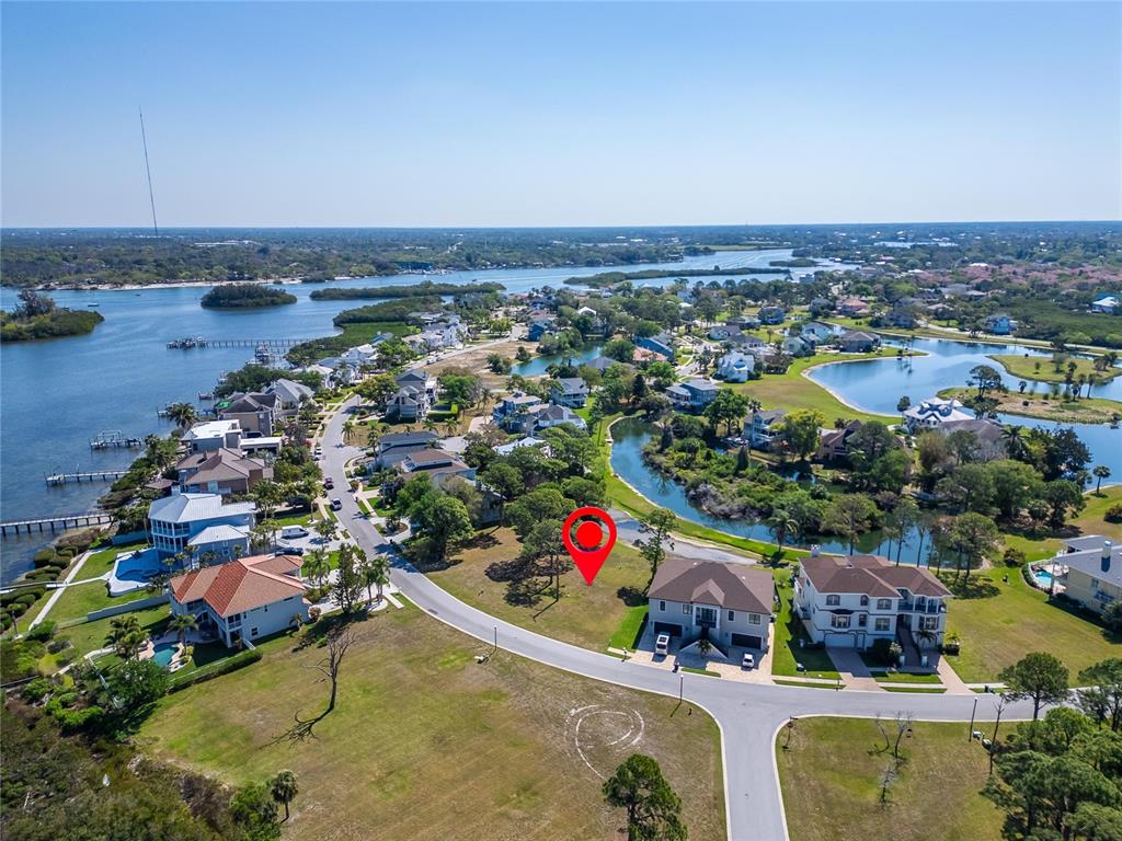 An aerial view shows a vacant residential lot marked by a red pin near water — N POINTE ALEXIS DRIVE, TARPON SPRINGS, FL