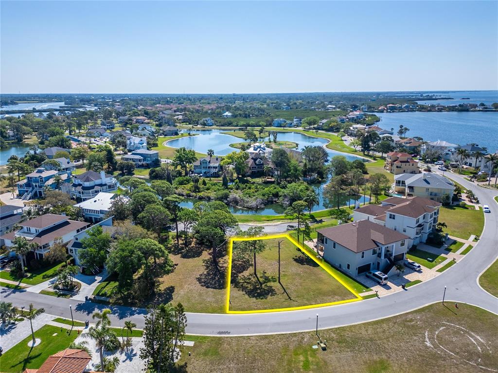 An aerial view shows a vacant residential lot highlighted in yellow within a coastal neighborhood — N POINTE ALEXIS DRIVE, TARPON SPRINGS, FL