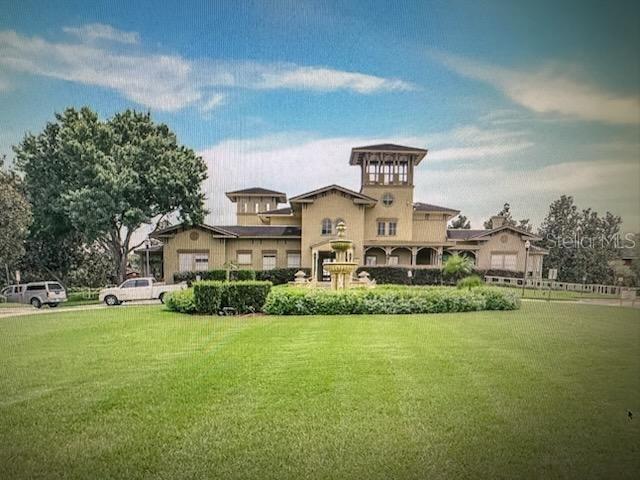 A large, multi-story tan house with a central fountain and a sprawling front lawn — 132 VISTA VERDI CIRCLE UNIT 100, LAKE MARY, FL