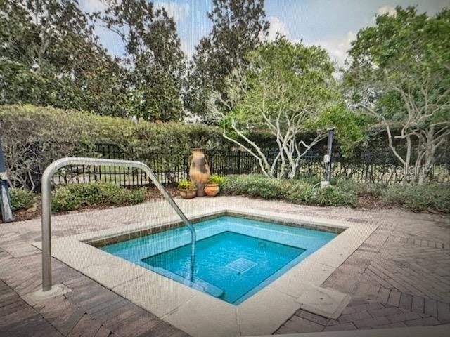 A square in-ground spa with a metal handrail sits on a brick patio outdoors — 132 VISTA VERDI CIRCLE UNIT 100, LAKE MARY, FL