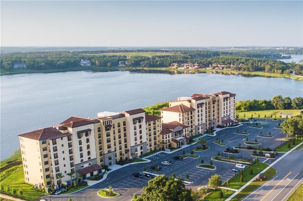 An aerial view shows a large multi-story apartment complex situated next to a lake — 16300 COUNTY ROAD 455 UNIT 607, MONTVERDE, FL
