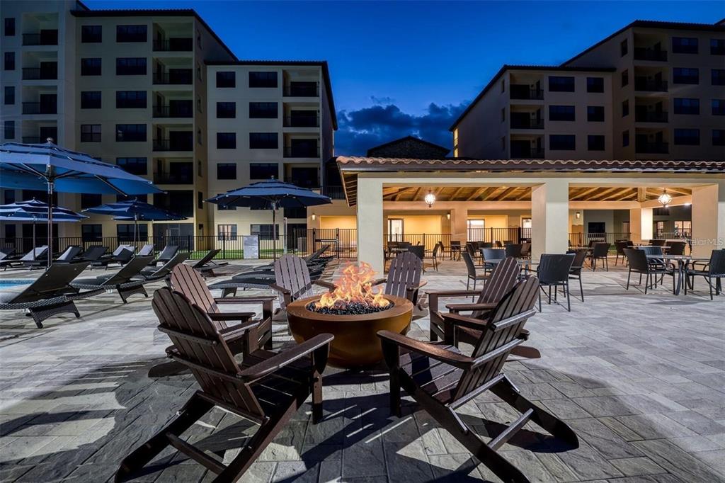 An outdoor patio area features a fire pit surrounded by wooden chairs at dusk — 16300 COUNTY ROAD 455 UNIT 607, MONTVERDE, FL