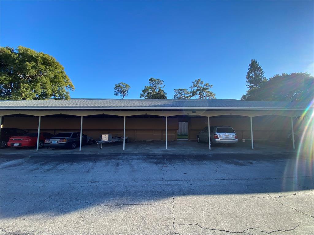 A covered parking structure with multiple bays sits in front of a residential building — 525 GEORGETOWN DRIVE UNIT F, CASSELBERRY, FL