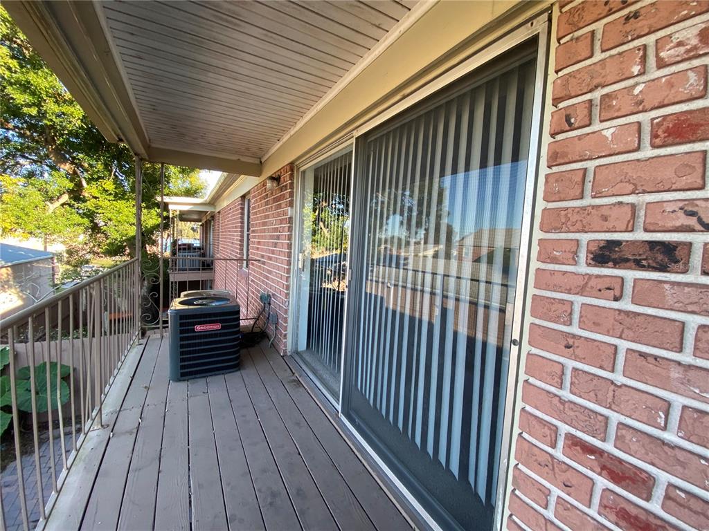 A wooden balcony features a Goodman air conditioning unit and a sliding glass door — 525 GEORGETOWN DRIVE UNIT F, CASSELBERRY, FL