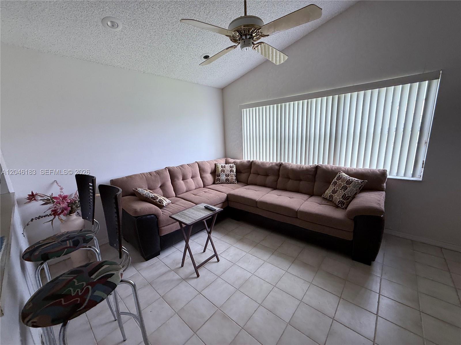 A living room features a large brown sectional sofa, tile flooring, and a ceiling fan — 11185 Rios Rd, Boca Raton FL 33498, BOCA RATON, FL