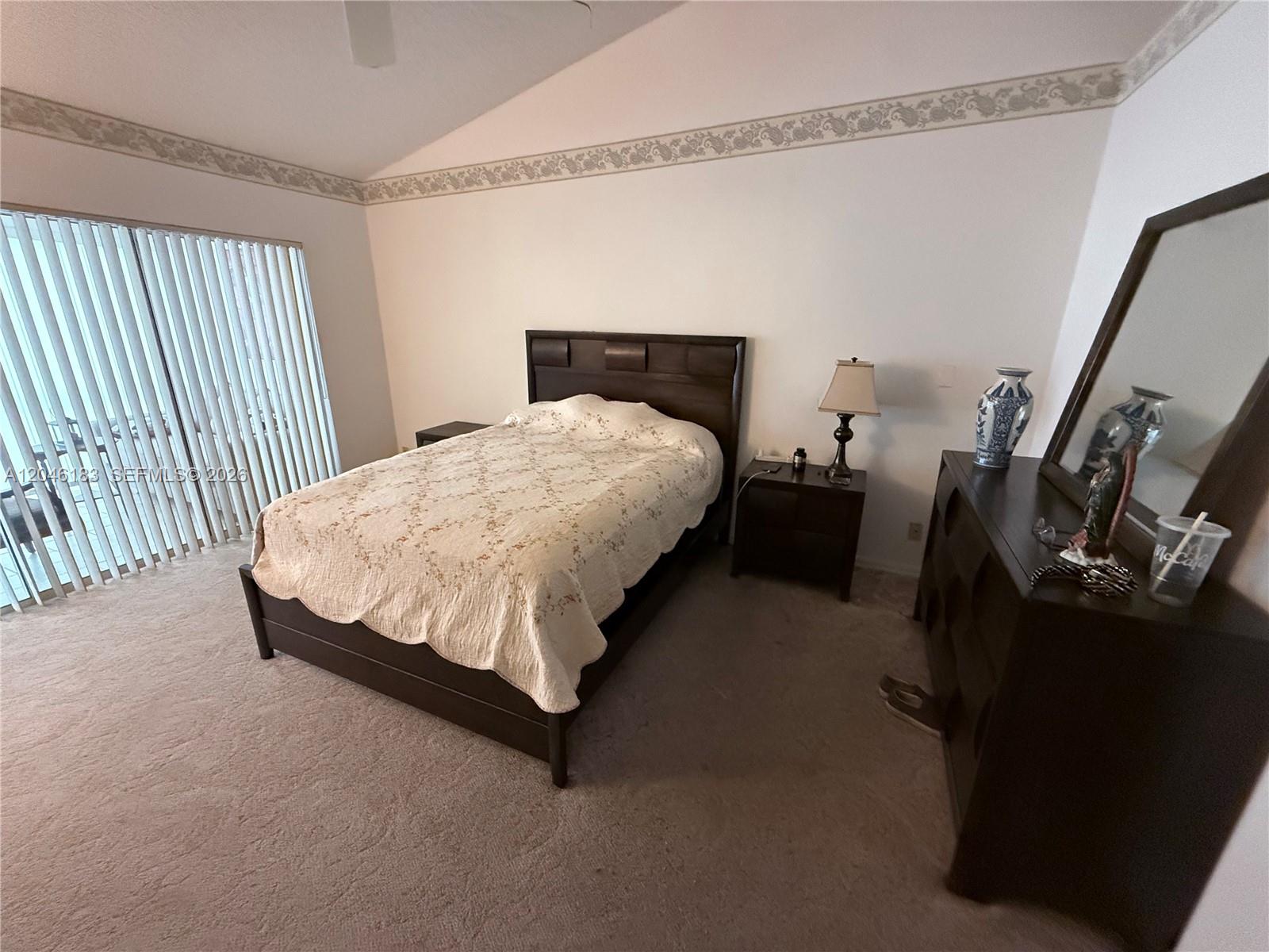 A bedroom features a dark wood bed frame, matching nightstands, a dresser with mirror, and carpet — 11185 Rios Rd, Boca Raton FL 33498, BOCA RATON, FL