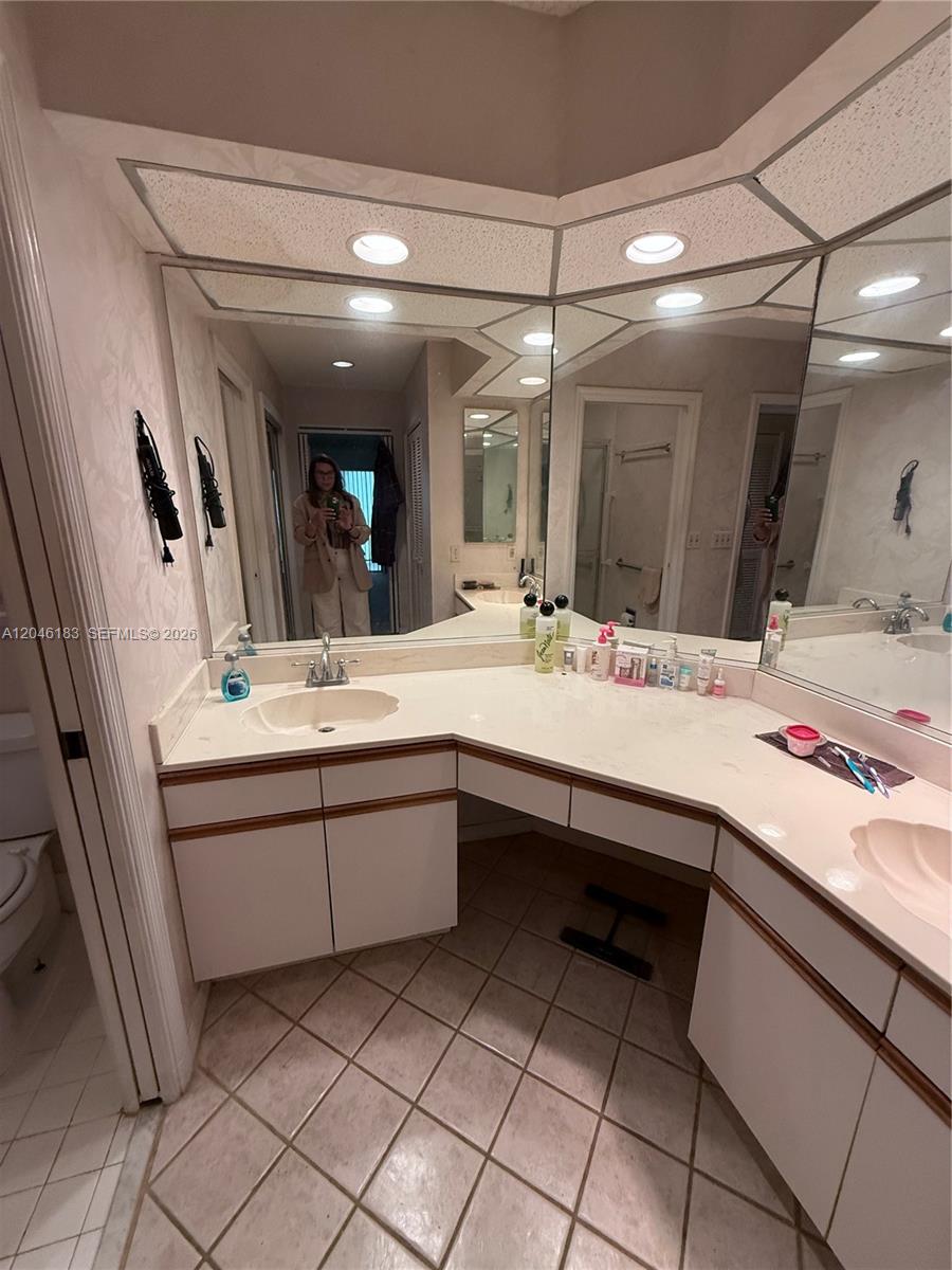 A bathroom features a dual-sink vanity with white countertops, wood trim, and a large mirror — 11185 Rios Rd, Boca Raton FL 33498, BOCA RATON, FL