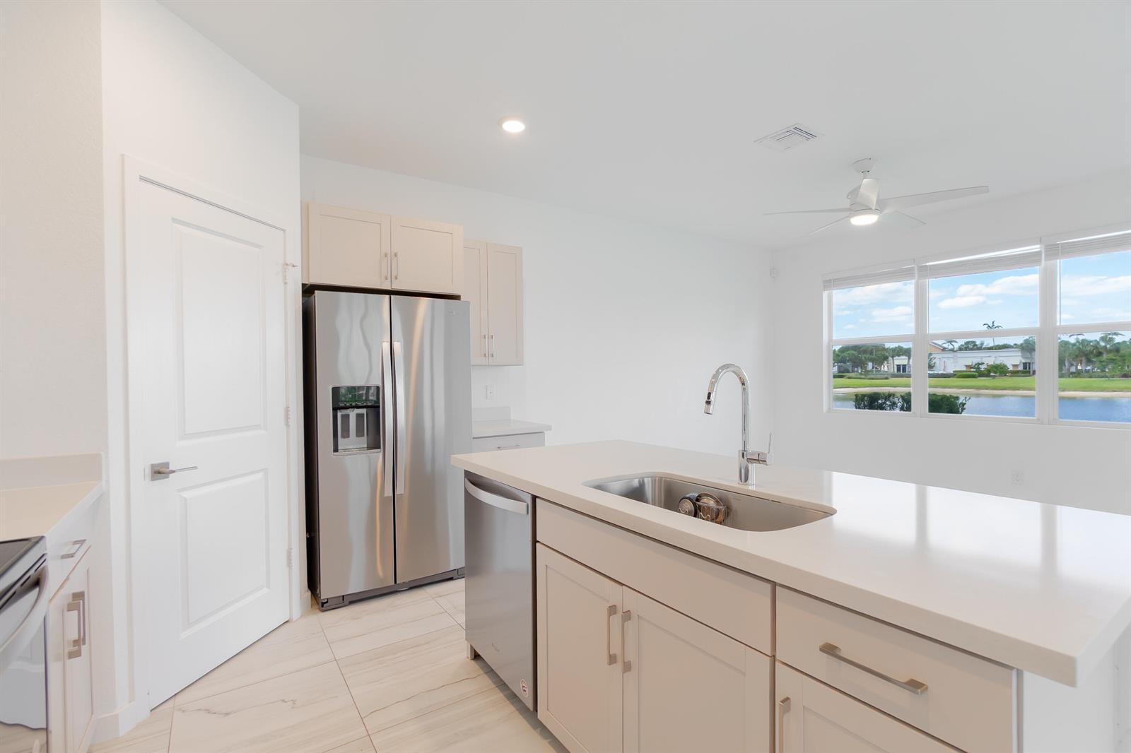 A modern kitchen features light-colored cabinetry, stainless steel appliances, a center island, and water views — 8618 Via Mar Rosso, Lake Worth FL 33467, LAKE WORTH, FL