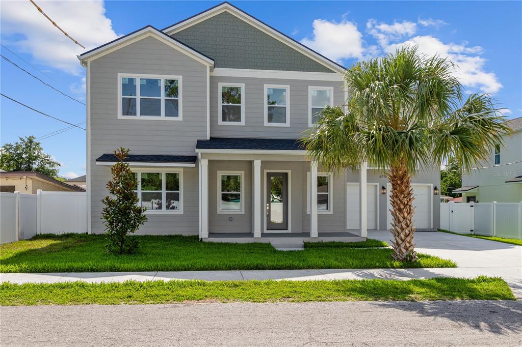 A two-story gray house with a front porch, a palm tree, and a concrete driveway — 6710 N 17TH STREET, TAMPA, FL