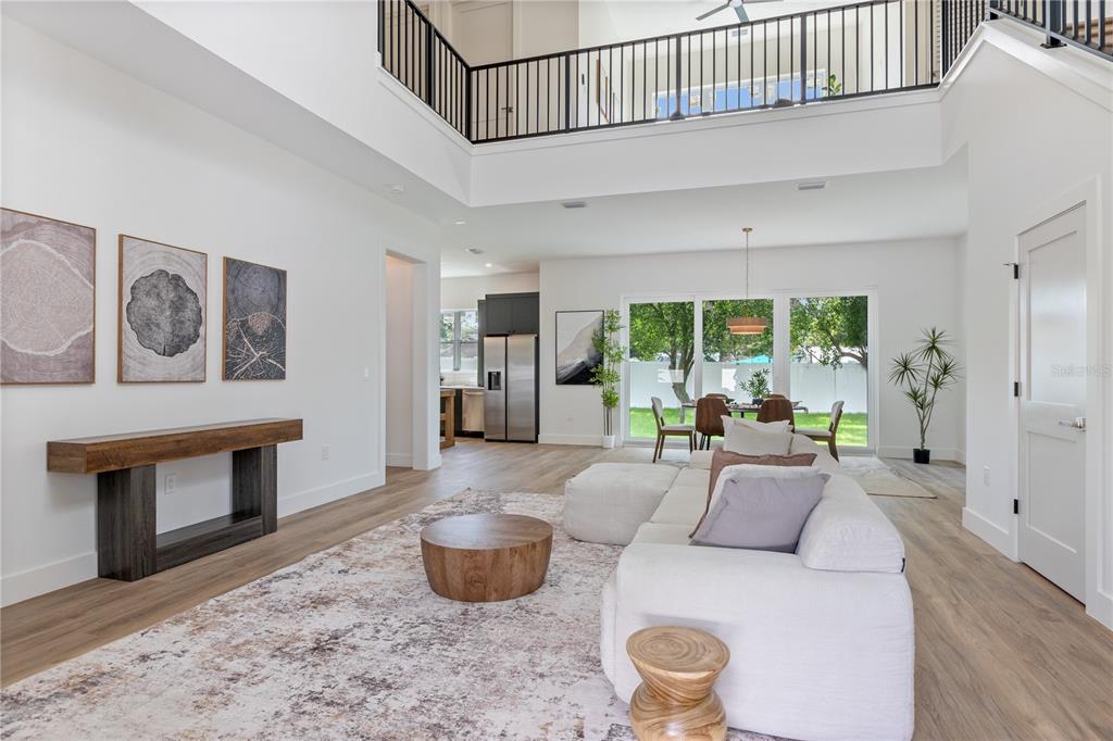 A bright, open-concept living room features a high ceiling, white walls, and wood-look flooring — 6710 N 17TH STREET, TAMPA, FL