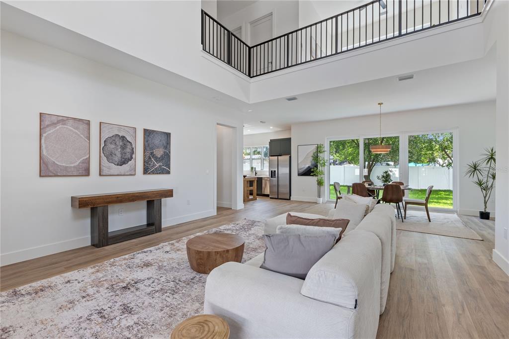 A bright, open-concept living and dining area features high ceilings, white walls, and wood flooring — 6710 N 17TH STREET, TAMPA, FL