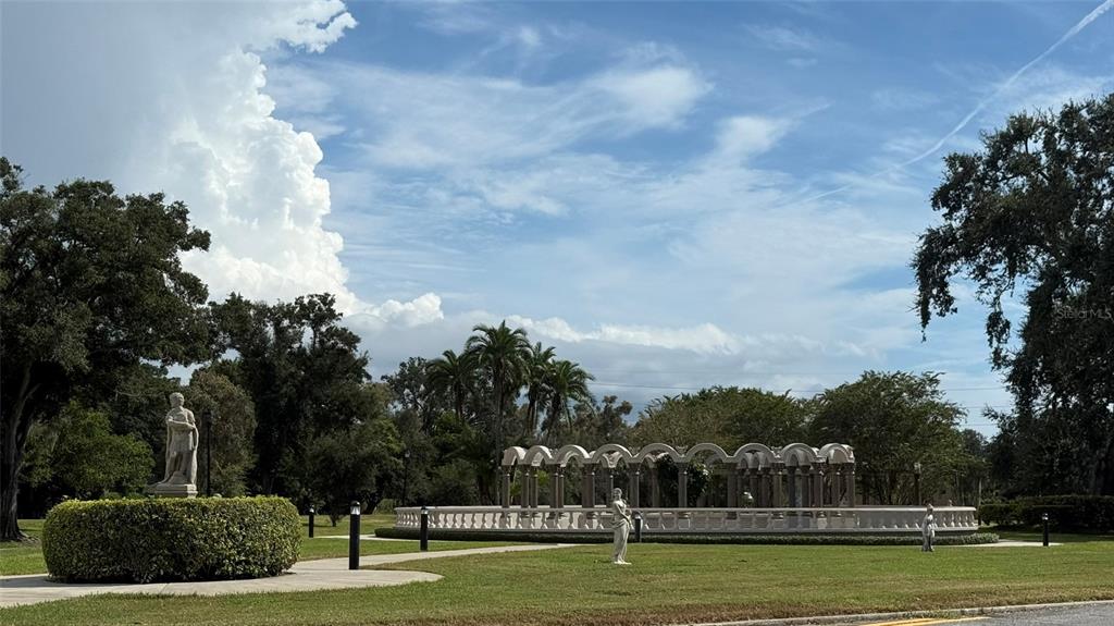 A stone colonnade and statues stand in a grassy park under a cloudy sky — 2460 CANADIAN WAY UNIT 48, CLEARWATER, FL