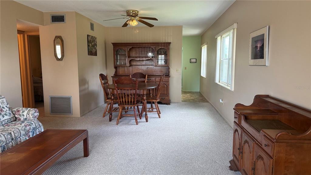 A dining area with a wooden hutch and table set sits on carpeted flooring — 2460 CANADIAN WAY UNIT 48, CLEARWATER, FL