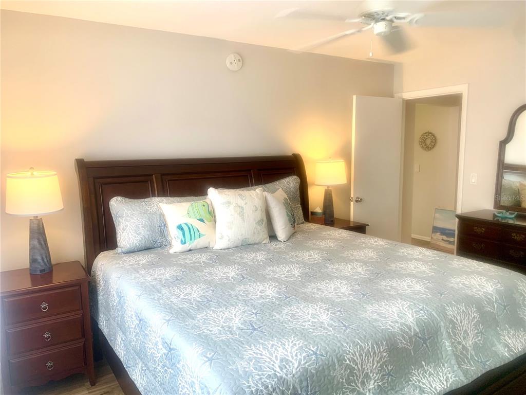 A bedroom features a wooden bed frame, patterned bedding, and two matching bedside lamps — 2310 CANALBLUFF PLACE UNIT V287, SARASOTA, FL