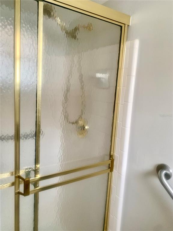 A glass shower enclosure features a gold-toned metal frame and a matching towel bar — 2310 CANALBLUFF PLACE UNIT V287, SARASOTA, FL