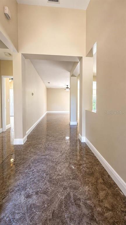 A hallway with high ceilings and polished brown marble-look tile flooring leads into a room — 1448 DERBY GLEN DRIVE, ORLANDO, FL