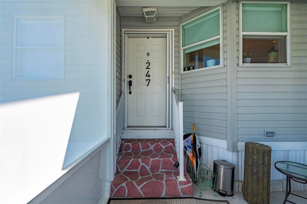 The exterior entrance features a white door with the number 247 and stone steps — 1000 KINGS HIGHWAY UNIT 247, PORT CHARLOTTE, FL