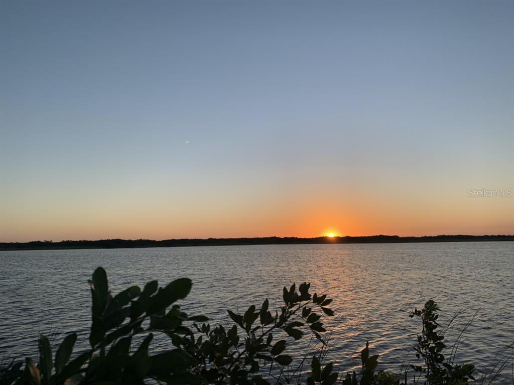 A sunset view over a lake with silhouetted foliage in the foreground — 9448 ST MARYS COURT, PORT CHARLOTTE, FL