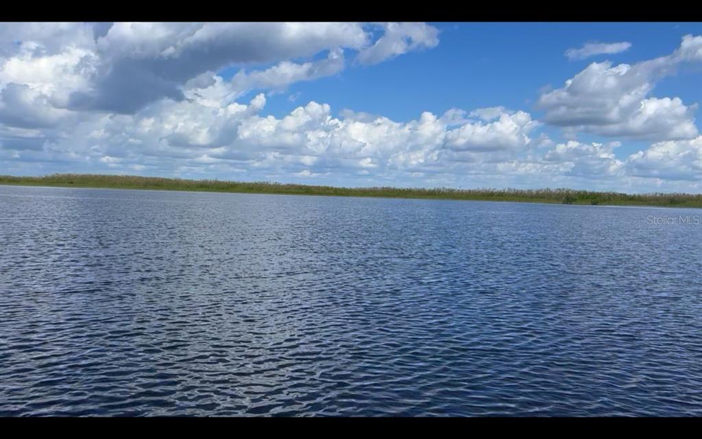 A view of a calm lake under a blue sky with scattered white clouds — 9448 ST MARYS COURT, PORT CHARLOTTE, FL