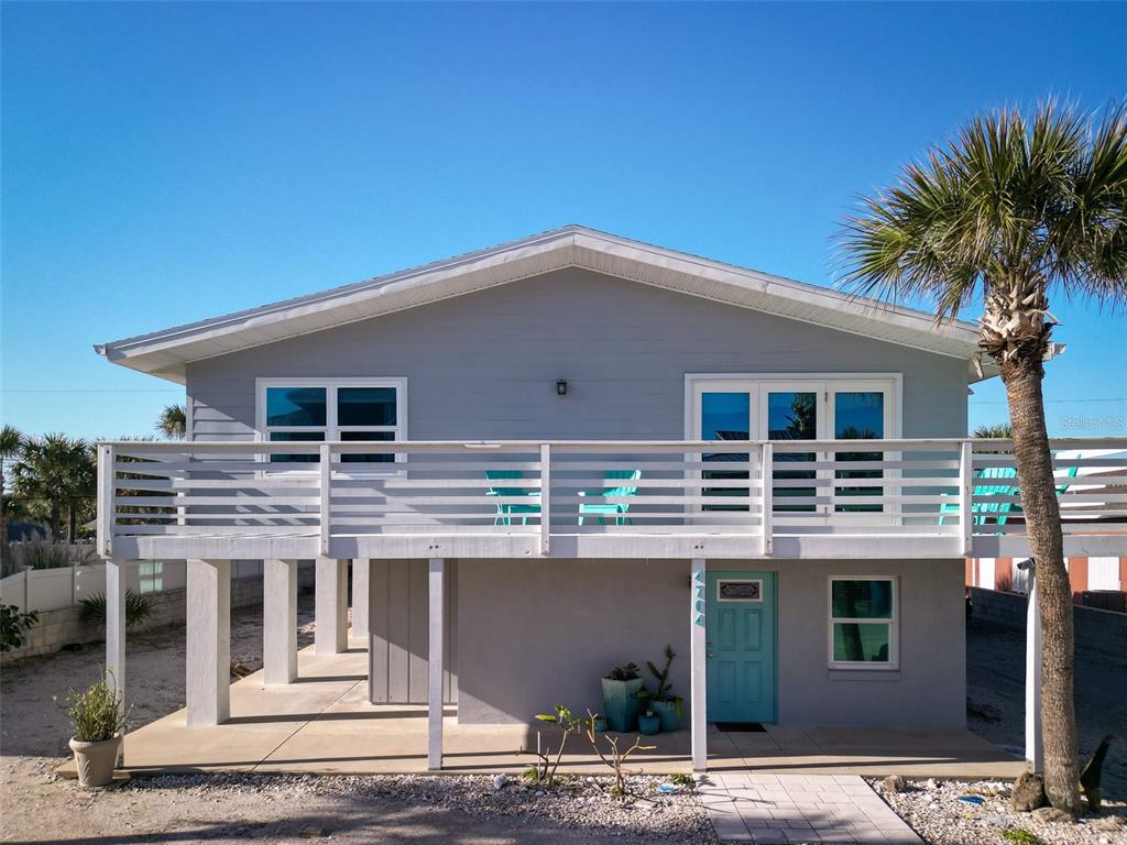 A two-story house with a gray exterior, a white balcony, and a teal front door — 4704 VAN KLEECK DRIVE, NEW SMYRNA BEACH, FL