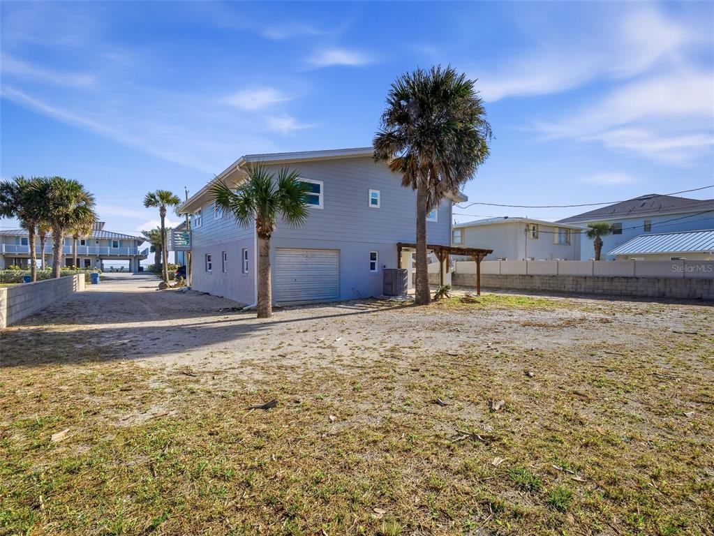 A light blue two-story house with a garage and palm trees on a sandy lot — 4704 VAN KLEECK DRIVE, NEW SMYRNA BEACH, FL