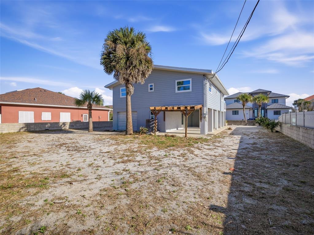 The exterior of a two-story light blue house with a pergola and a sandy yard — 4704 VAN KLEECK DRIVE, NEW SMYRNA BEACH, FL